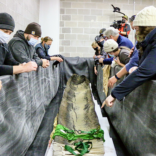 A team looks on as the canoe has been placed in it's special preservation at the SAPF.