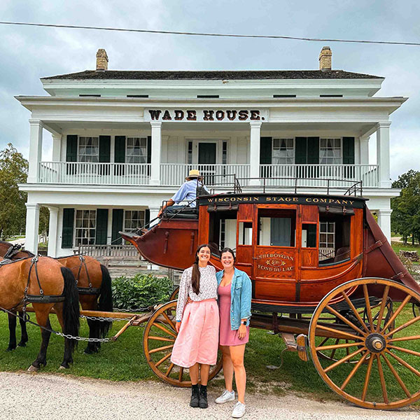 Two women pose with the horse-drawn Wisconsin Stage Company coach in front of Wade House
