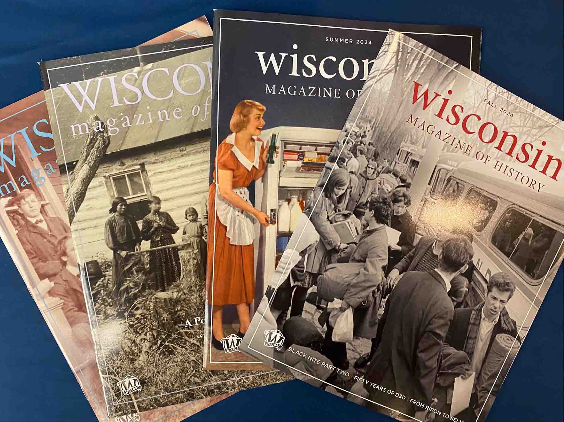 Four covers of the Wisconsin Magazine of History with a dark blue background