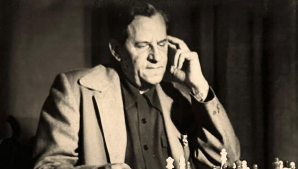 Black and white photo of an older man looking down at a chess board