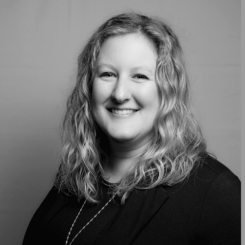 Black and white image of a woman with curly blonde hair smiling at the camera