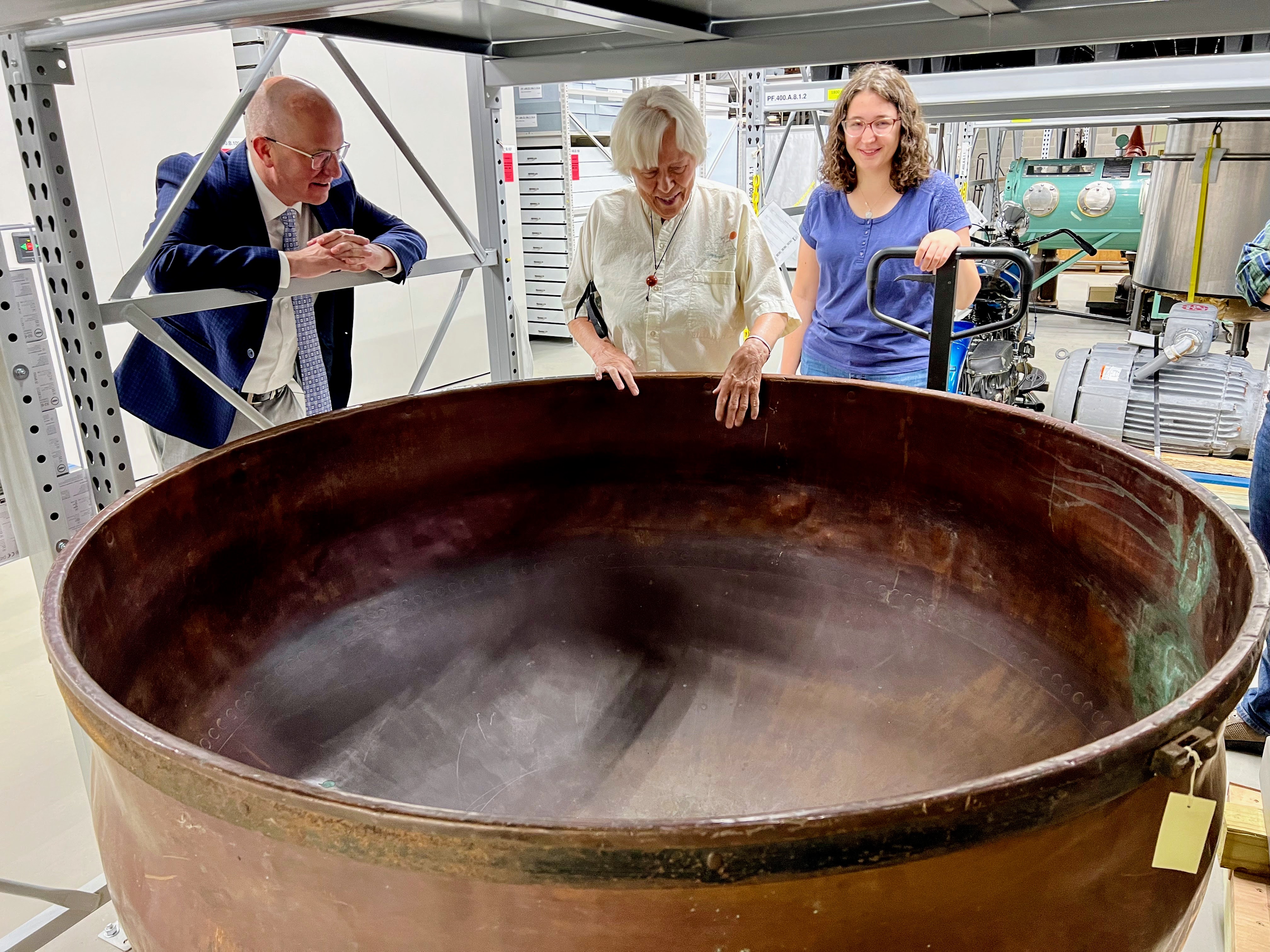 Mary Hilfiker (center) examines the copper kettle from her parents’ Tuscobia Cheese Factory during a 2022 visit to the State Archive Preservation Facility in Madison. Also pictured are Joe Kollar (left) of the Wisconsin Historical Foundation and Bethany Johnson, a UW-Eau Claire student who received the Mary L. Hilfiker Scholarship for students from Rice Lake High School, Hilfiker’s alma mater. Photo by Dean Witter