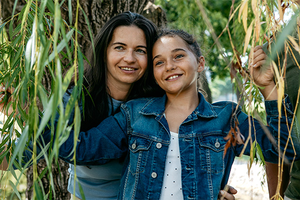 A mother and daughter peak through the willow branches at a historic site