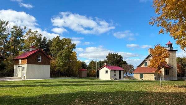 Historic property grounds with a a brick light station and two other outbuildings in fall