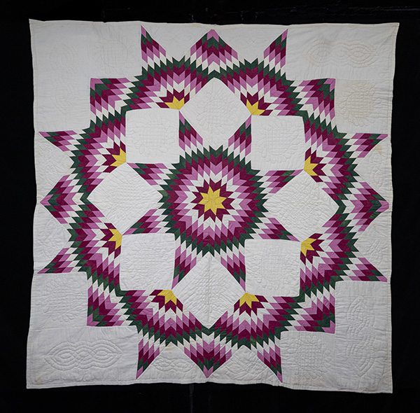 A purple, yellow, green and white kaleidoscope looking quilt. Broken Star Quilt 2025.115.1
