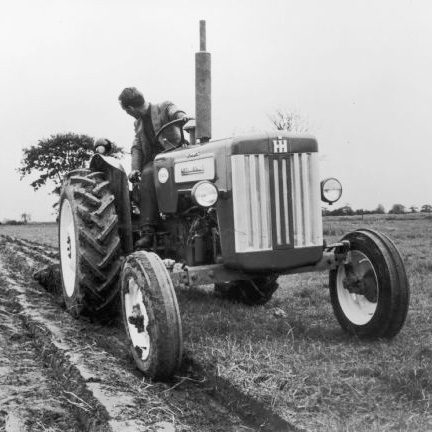 A man plows a field with a British B-414 diesel tractor.