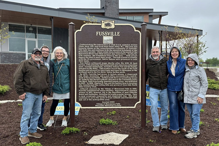 Community members pose with a two-post historical marker featuring the Fussville settlement near present-day Menomonee Falls