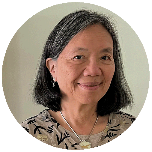 Lorna Young with black hair with traces of gray wearing a printed top smiling at the camera.