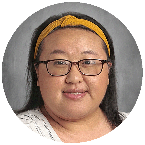 A woman with straight black hair in a yellow headband, wearing glasses, smiling at the camera.