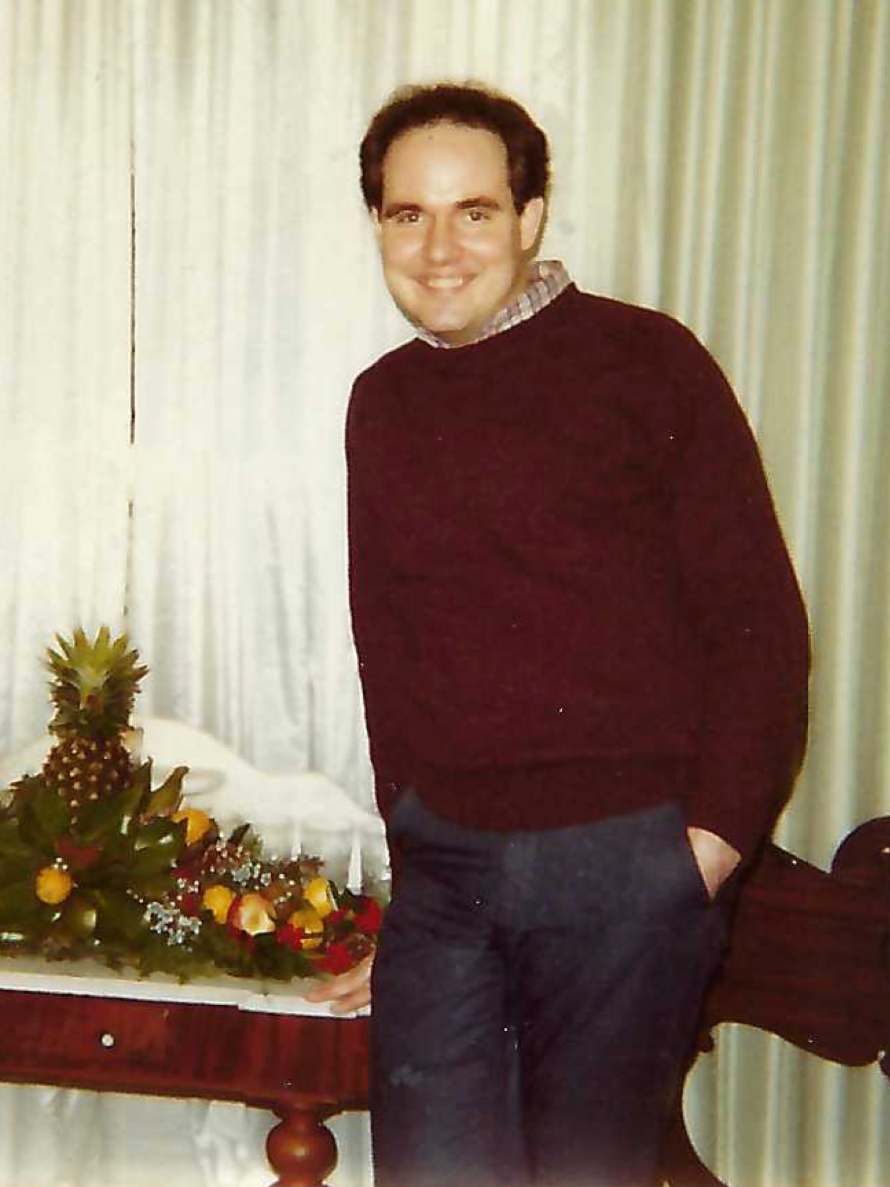 David Carter informal portrait, smiling, medium short hair, a burdundy knit sweater with a plaid collar from a button up poking out.