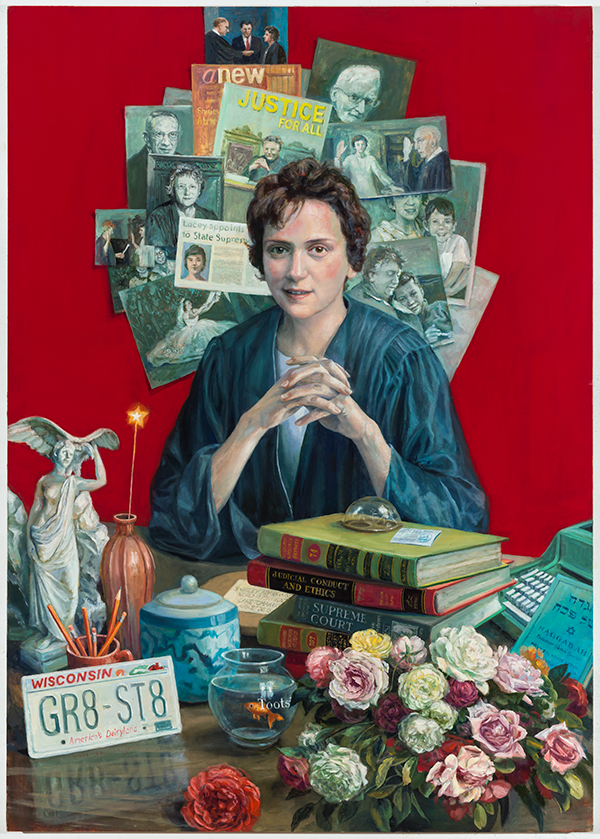 Shirley Abrahamson's portrait with her seated at a desk in her judge robes. Behind her are a variety of newspapers, pictures, and posters plastered to the wall in a circle/halo effect. In front of her on the desk there are a variety of items: Lady Justice, a vase, a sparkler, a stack of legal books, a jar, goldfish in a bowl, a arrangement of roses and other flowers, the Torah, a typewriter, pencils, and a Wisconsin license plate.