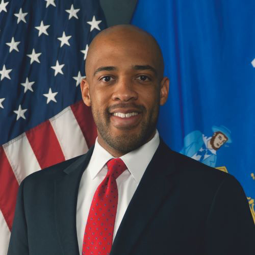Lieutenant Governor Mandela Barnes smiles proudly at the camera in this portrait in front of the Wisconsin & US Flags.