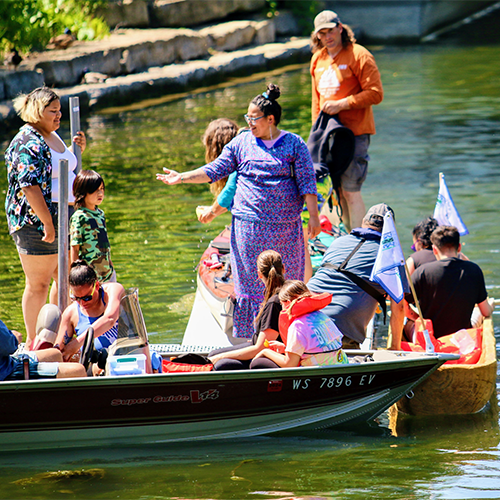 a group of 4 Ho-Chunk people exit the canoe and are greated by friends family and WHS staff members