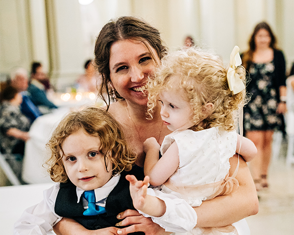 A bride happily cuddles two children at her wedding at the Wisconsin Historical Society Headquarters