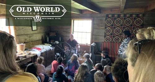 Old World Wisconsin. A group of children watch a woman working a spinning wheel during a field trip.