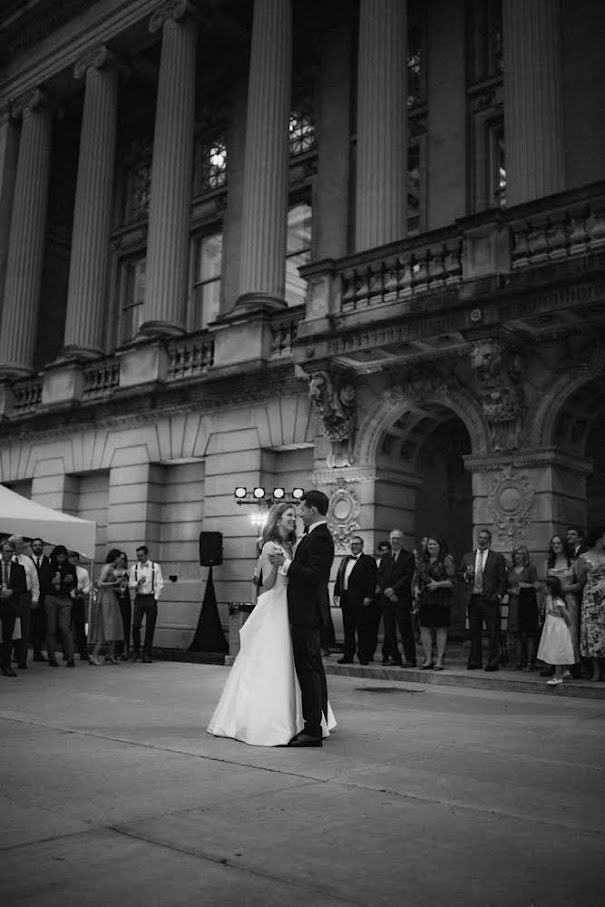 A black and white photograph of a hetero couple dancing on the terrace smiling at each other.