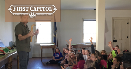 First Capitol. A group of students raise hands as an instructor works with the class.