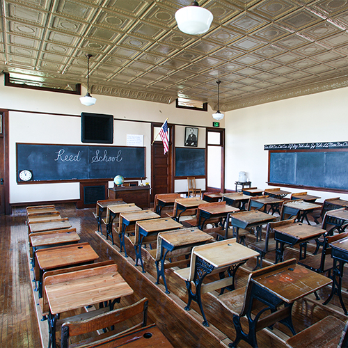 Inside the Reed School classroom, with vintage desks and a chalkboard